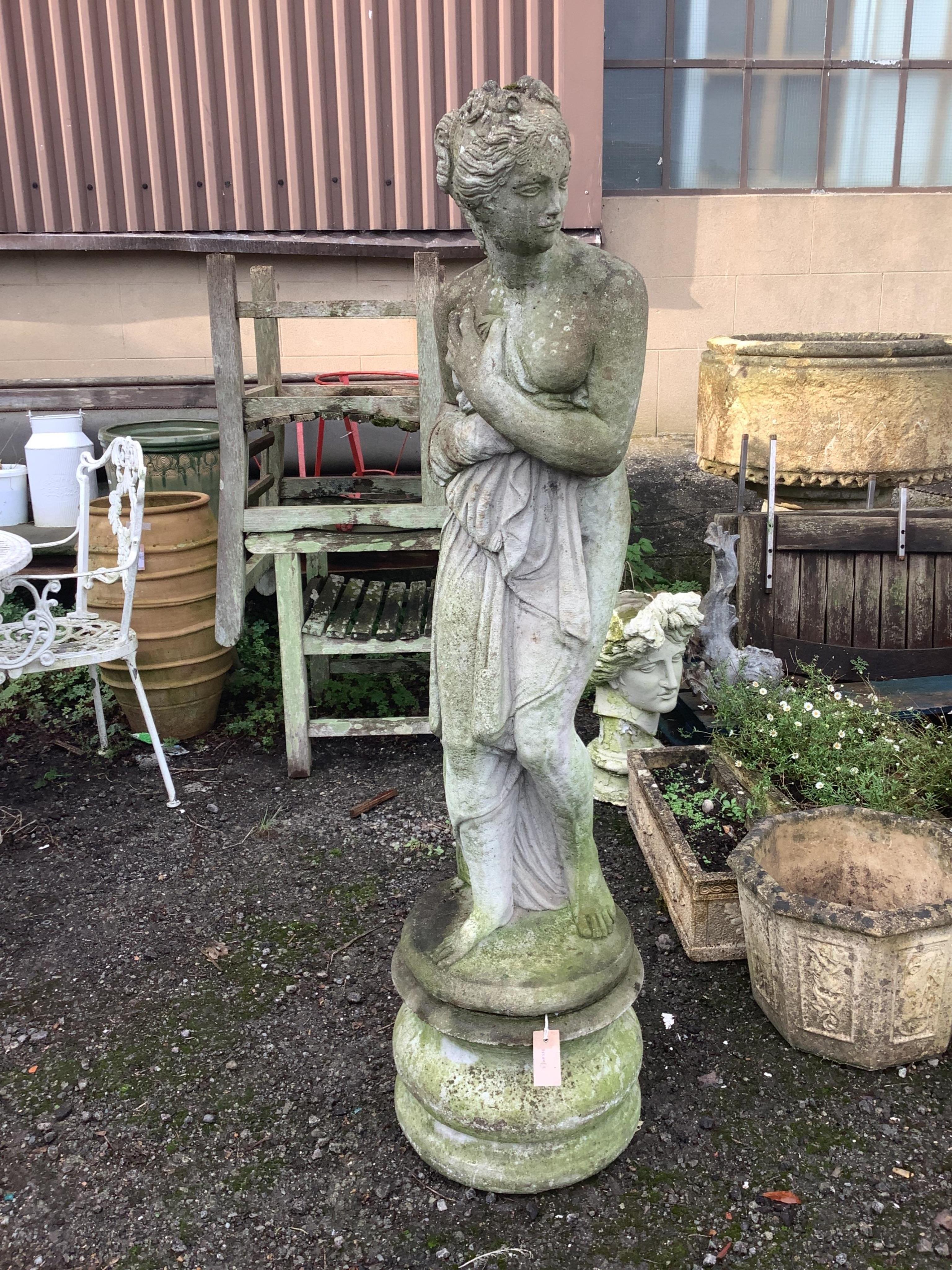 A reconstituted stone female bather garden ornament on a circular pedestal, height 144cm. Condition - fair